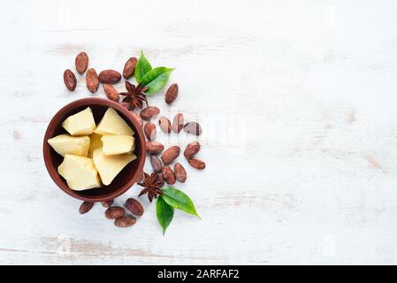 Burro di cacao in una ciotola sullo sfondo vecchio. Cacao in grani. Vista dall'alto. Spazio libero di copia. Foto Stock