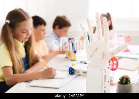 I bambini imparano in classe con la mano robotica umanoide in primo piano Foto Stock