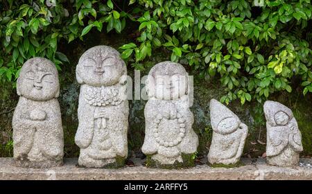 Le piccole monete sono lasciate alle antiche statue del tempio dei monaci buddisti. Queste piccolissime statue si trovano sul marciapiede fuori del Tempio di Arashiyama a Kyoto, Japa Foto Stock