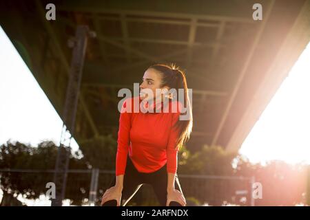 Attraente femmina giovane runner prendendo pausa dopo il jogging all'aperto Foto Stock