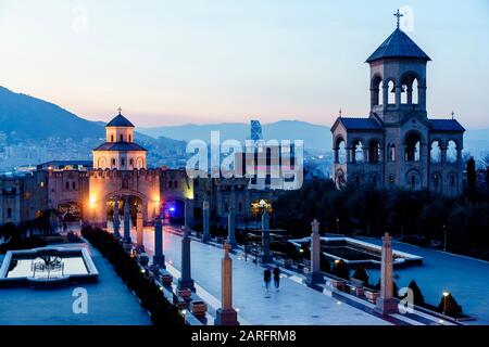 Ingresso al territorio della Cattedrale della Santissima Trinità a Tbilisi. Una foto della serata - luci, cielo blu scuro. Foto Stock