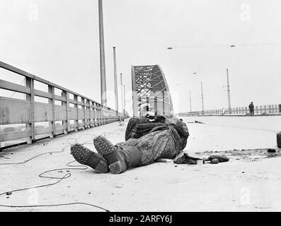 Operation Market Garden, Arnhem, Paesi Bassi, 1944: Il ponte a Nijmegen dopo essere stato catturato dalla 82nd (US) Airborne Division. Un SS tedesco morto si trova dove è caduto durante l'attacco. Si noti gli stivali pesanti e il vestito camouflage completo. Sullo sfondo destro, un lone GI pattrols Foto Stock