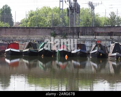 Alcune barche a remi ormeggiate sul canale Regents vicino a Kings Cross a Londra con la linea ferroviaria elettrificata dietro. Foto Stock