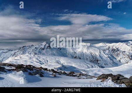 Vista dalla cima di la Masse nella località francese di Les Menuires attraverso le alpi. Una banca di nube siede sopra i picchi distanti. Foto Stock