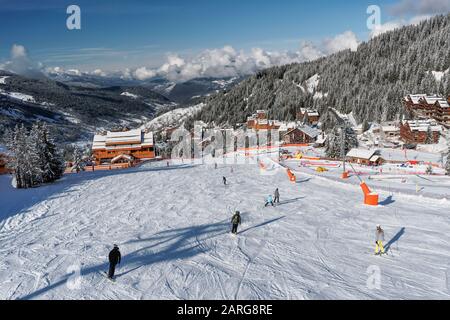 Sciare nella località francese di Meribel nelle tre valli, girato dalla telecabina Rhodos che guarda giù su piste e chalet a Rond Point Foto Stock