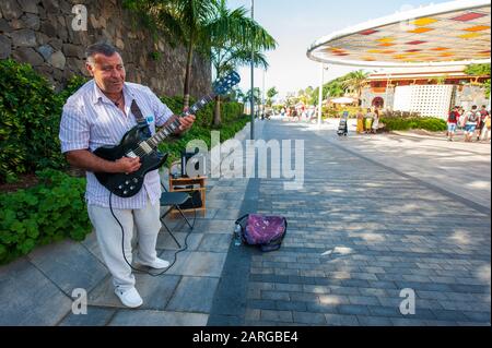 Canary ISLAND TENERIFE, SPAGNA - 27 dicembre 2019: Un artista di strada che suona la chitarra su plaza Duque. E' un viale con negozi vicino alla famosa spiaggia di P. Foto Stock
