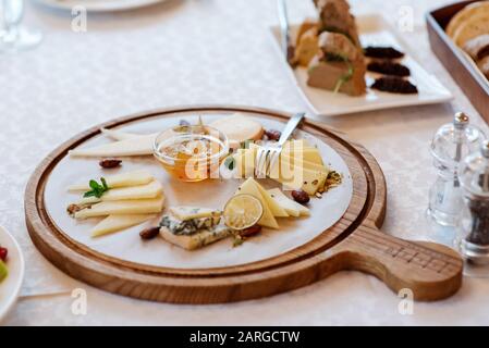 Confiture e formaggi tagliati su una tavola di legno. Assortimento di fette tagliate di diverse varietà di formaggio. Foto Stock