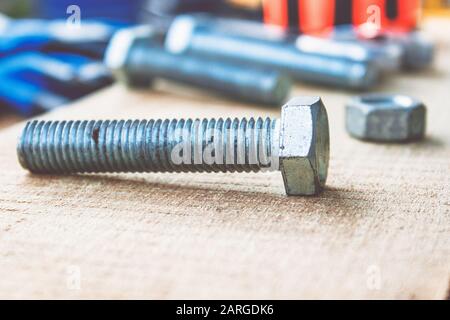Il bullone e le rondelle del dado in acciaio si trovano sulle tavole di legno. Il concetto di attrezzi e lavori di riparazione. Foto Stock