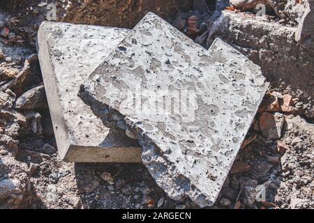 Pile di rifiuti da costruzione grigio e vecchi pezzi di cemento rotti giacenti su un cantiere come sfondo industriale testurizzato. Il concetto di ecolog Foto Stock