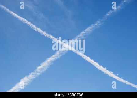 Contrails in cielo blu. Croce bianca fatta di tracce di vapore dai piani Foto Stock