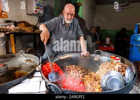 Uomo che cucina cibo in una pentola gigante, Bird Street, Kabul, Afghanistan, Asia Foto Stock