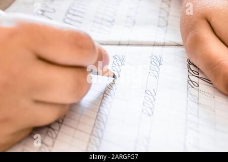 Scolari che scrivono da vicino. Matita nella mano dei bambini. Il ragazzo sta scrivendo. Foto Stock