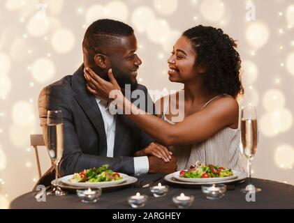 Attraente donna nera che tocca il suo uomo, coccolando nel ristorante Foto Stock