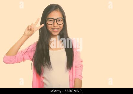 Studio shot di giovani asiatici felice ragazza sorridente e dando segno di pace Foto Stock