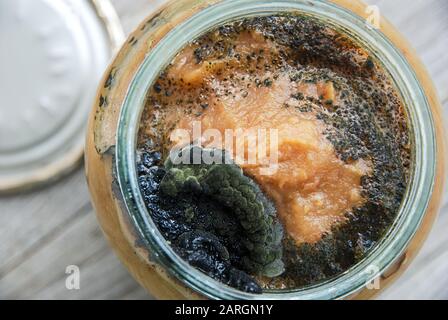 Aprire il vaso di vetro di marmellata di mele fatta in casa con stampo scuro sulla parte superiore. Conservazione impropria di cibo inscatolato domestico. Foto Stock