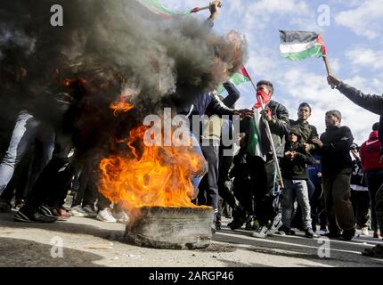 Gaza, La Striscia Di Gaza, La Palestina. 28th Gen 2020. I dimostranti palestinesi incanta slogan e battono bandiere palestinesi mentre si trovano a scagliare pneumatici durante una protesta contro la prevista proposta di piano di pace del presidente americano Donald Trump a Gaza il 28 gennaio 2020. Credit: Mahmoud Issa/Quds Net News/Zuma Wire/Alamy Live News Foto Stock