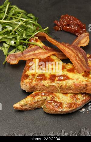 Formaggio su pane tostato con pancetta e contorno Foto Stock