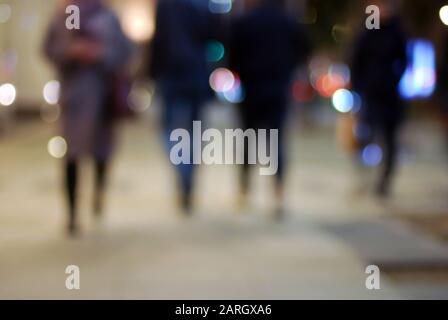 Silhouette di persone sfocate sulla strada notturna in grandi luci della città Foto Stock