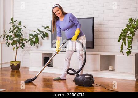 Bella donna incinta ama pulire la sua casa. Foto Stock