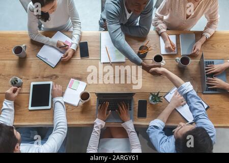 Vista dall'alto dei colleghi che si scuotono le mani durante la riunione di gruppo Foto Stock