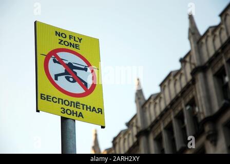 Segno che vieta drone battenti con iscrizione "no fly zone" in inglese e russo Foto Stock