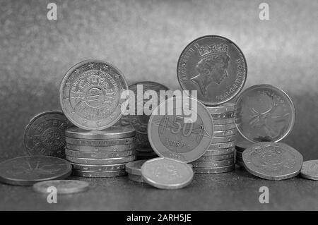 Pile di monete di diverse nazioni con euro e Centesimi di fronte a sfondo d'argento Foto Stock