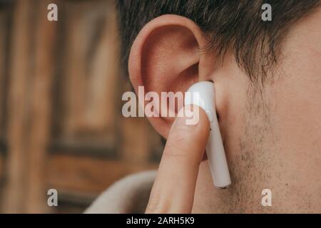 Uomo che modifica il volume dell'auricolare wireless Foto Stock