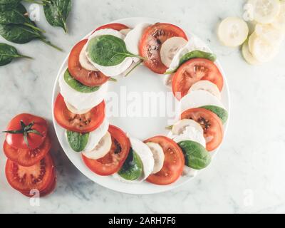 Mangiare sano, insalata caprese. Cena vegetariana. Pomodoro fresco a fette, mozzarella e basilico. Dieta mediterranea. Piastra bianca Foto Stock