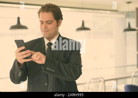 Uomo d'affari iraniano in tuta utilizzando il telefono a casa Foto Stock