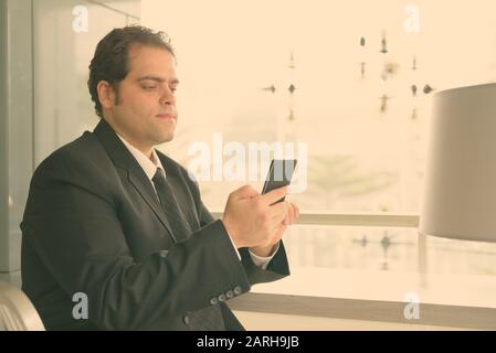 Uomo d'affari iraniano in tuta utilizzando il telefono a casa Foto Stock