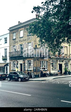 Londra/UK - 17/07/2019: Persone seduti ai tavoli appena fuori dal King William IV Pub che gustano le loro bevande. I pub sono una struttura sociale per bere Foto Stock