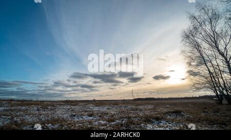 Bella impostazione del sole su campo ghiacciato Foto Stock