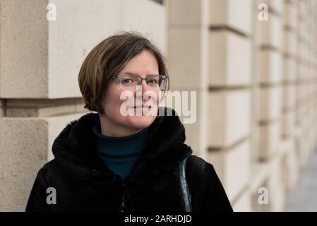 Ritratto di una donna attraente di trent'anni con un cappotto invernale nero, che si erge contro un vecchio muro Foto Stock