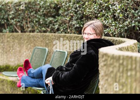 Ritratto di una donna attraente di trent'anni con una giacca invernale nera, seduta rilassata Foto Stock