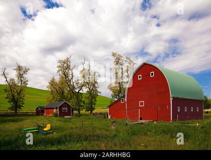 Grande fienile rosso nei pressi di campi di grano in una giornata parzialmente soleggiata nella zona di Palouse dello stato di Washington Foto Stock