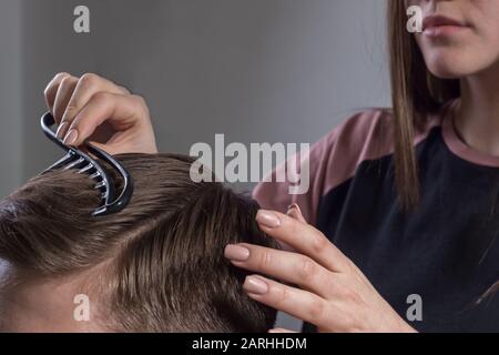 Close-up. Master parrucchiere non per lo styling dei capelli in modo che il barbuto guy pettinate i capelli con un pettine. Muschio di stile e bellezza. Barbershom. Il parrucchiere Foto Stock