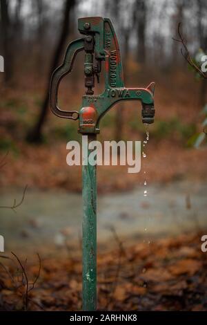 Antica pompa all'aperto in una fattoria, che perde in una giornata piovosa Foto Stock