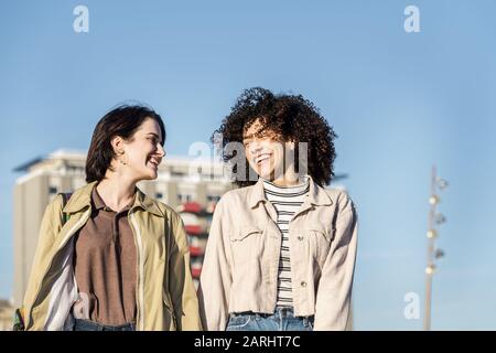 coppie interrazziali di giovani donne camminano intorno alla città mentre ridono divertente e felice, concetto di amicizia femminile e diversità razziale Foto Stock