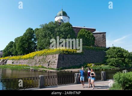 Vyborg, Regione di Leningrado, Russia - 8 giugno 2019: Gruppo di turisti a piedi sul terrapieno vicino al castello medievale di Vyborg sull'isola Foto Stock
