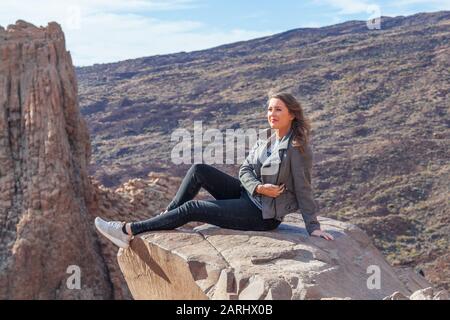 giovane donna seduta su roccia affioramento Foto Stock