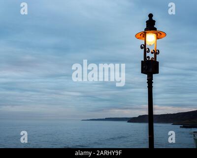 Lampada da strada decorata al tramonto e vista sulla South Bay da Scarborough Spa Scarborough North Yorkshire Inghilterra Foto Stock