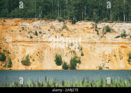 Alta spiaggia rocciosa e ripida coperta di pini un lago limpido e blu Foto Stock