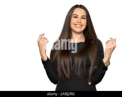 La ragazza con i capelli scuri è emozionalmente felice e sorridente. Una giovane donna con i capelli scuri e i vestiti scuri su uno sfondo isolato nel monolocale. La donna ha le labbra grandi del moncone e i capelli lunghi Foto Stock