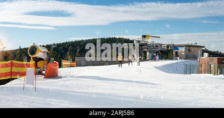 A Winterberg, la pista da sci nella zona di Kappe è coperta di neve artificiale. Si possono vedere impianti di risalita, cannoni da neve, sciatori sconosciuti. Sta nevicando. Foto Stock