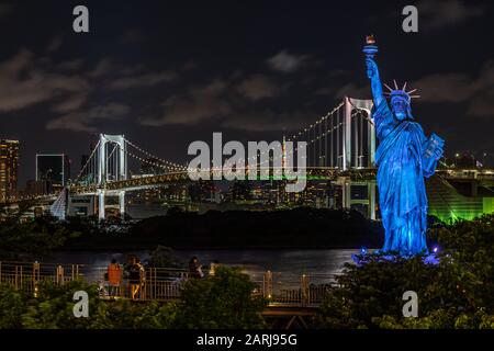 Vista notturna della replica della Statua della libertà e del Rainbow Bridge che collega il centro di Tokyo all'isola artificiale di Odaiba, Giappone Foto Stock