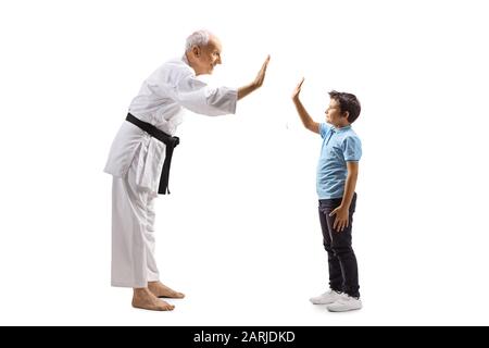 Profilo a tutta lunghezza di un ragazzo e un anziano maestro di karate gesturante alto-cinque isolato su sfondo bianco Foto Stock