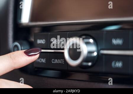 Giovane adulto donna che sceglie la modalità sul cruscotto dell'automobile Foto Stock