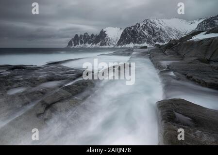 Tugeneset costa rocciosa con le montagne sullo sfondo durante le tempeste, Norvegia Foto Stock