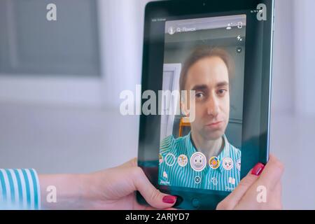 Donna che utilizza Snapchat multimedia messaging app con maschera facciale su tablet Foto Stock