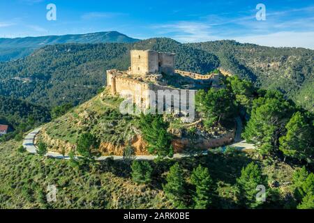 Veduta aerea del castello di Jalance in Spagna su una collina del 12th secolo costituito da cortile interno del castello, forma irregolare parete esterna con torre rotonda Foto Stock